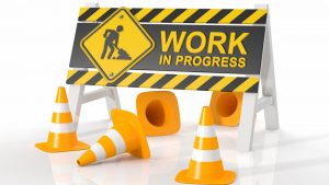 yellow "work in progress" construction sign with caution cones